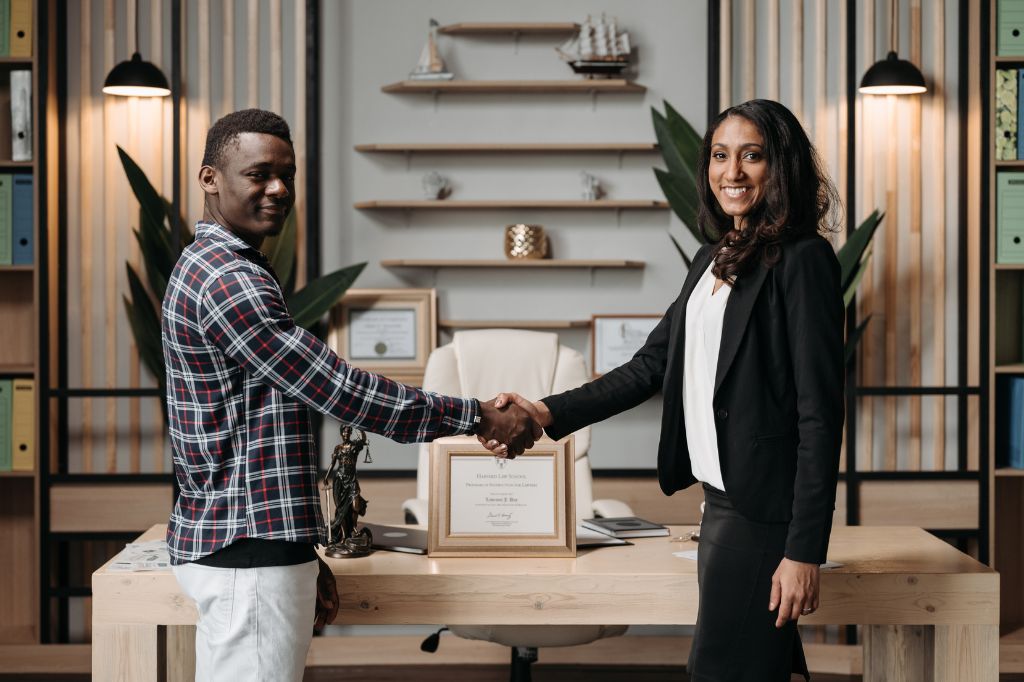 A roofer and realtor shake hands in an office