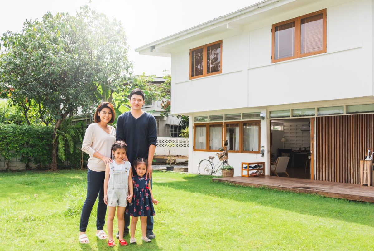 A family posing for a roofing testimonial in front of their home