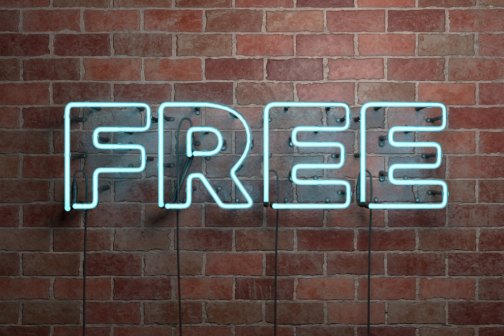 The word Free written in neon letters on a brick wall